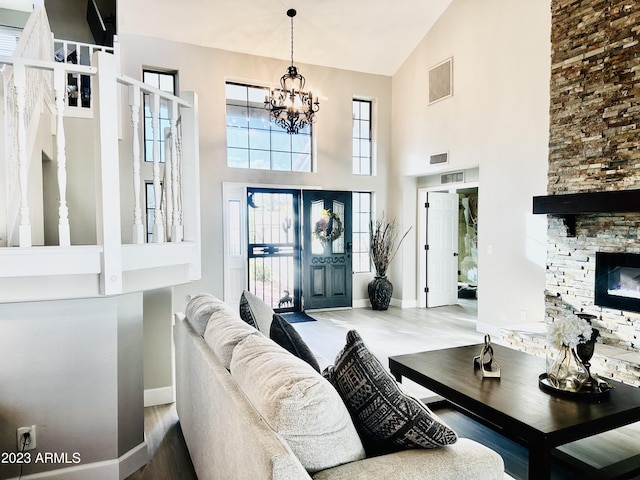 interior space featuring visible vents, baseboards, a chandelier, a stone fireplace, and a high ceiling