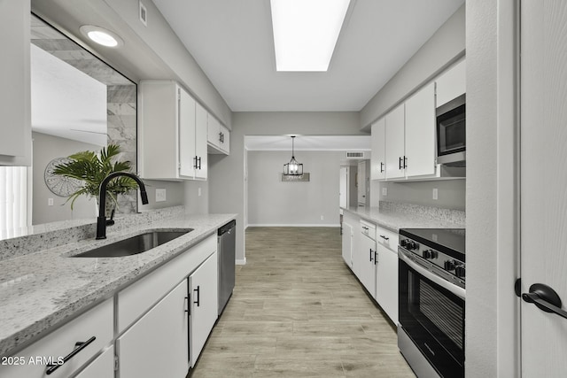 5148 E Edgewood Cir, Mesa, AZ 85206 - kitchen featuring appliances with stainless steel finishes, white cabinets, light wood-style floors, light stone countertops, and decorative light fixtures