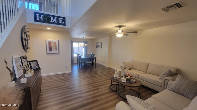 living room with ceiling fan with notable chandelier and dark hardwood / wood-style flooring