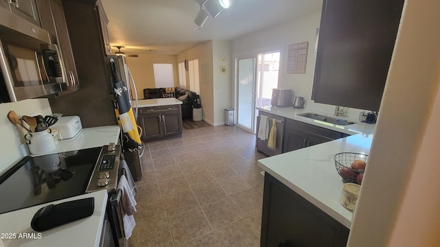 kitchen featuring light tile patterned flooring, appliances with stainless steel finishes, sink, ceiling fan, and dark brown cabinetry