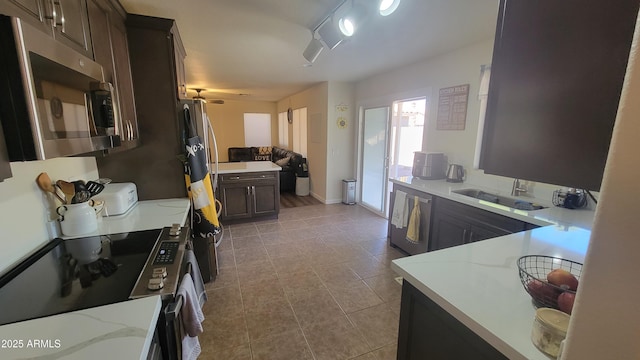 kitchen featuring sink, ceiling fan, appliances with stainless steel finishes, dark brown cabinetry, and light stone countertops