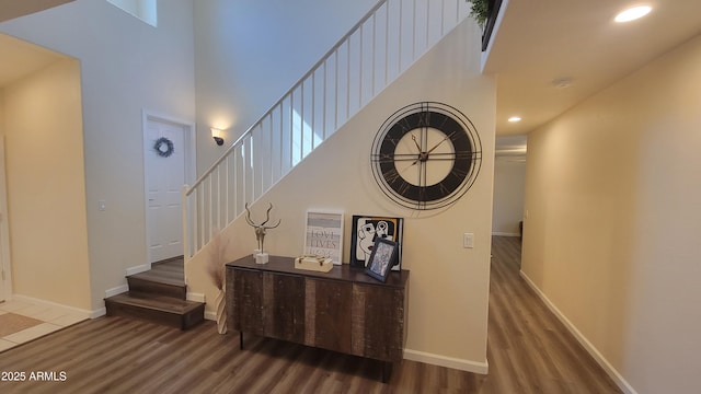 stairway with wood-type flooring and a towering ceiling