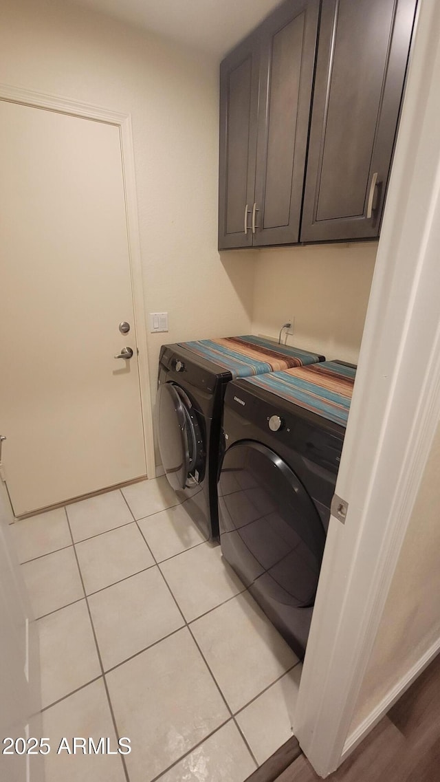 laundry room featuring separate washer and dryer, light tile patterned floors, and cabinets