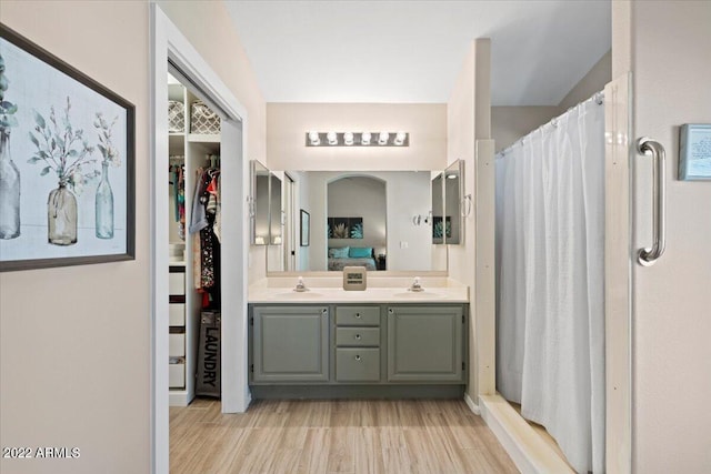 bathroom featuring walk in shower, vanity, and wood-type flooring