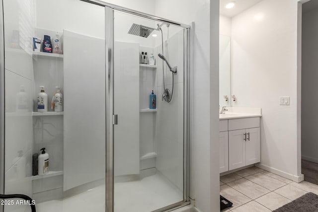 full bath featuring tile patterned floors, baseboards, a stall shower, and vanity