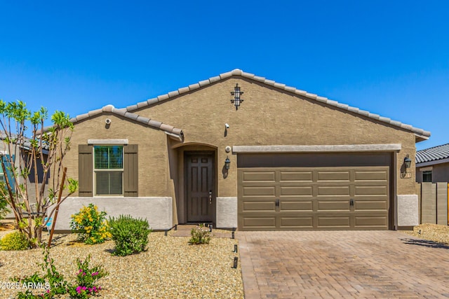 view of front of house with a garage, stucco siding, decorative driveway, and a tiled roof