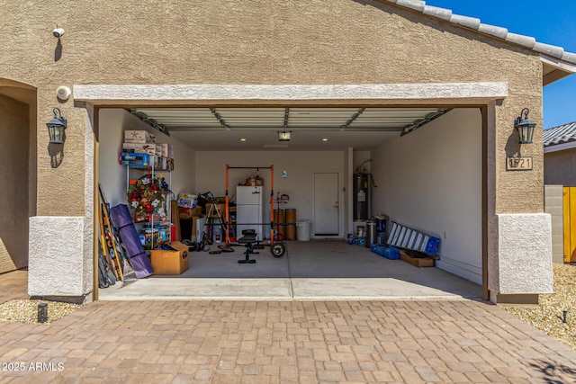 garage featuring a garage door opener, water heater, and driveway