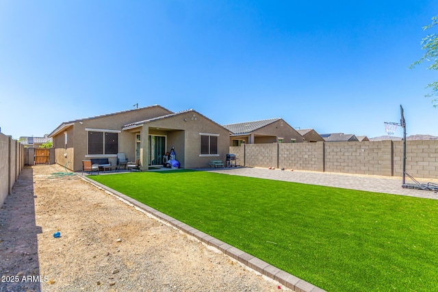 back of property featuring stucco siding, a patio area, a yard, and a fenced backyard