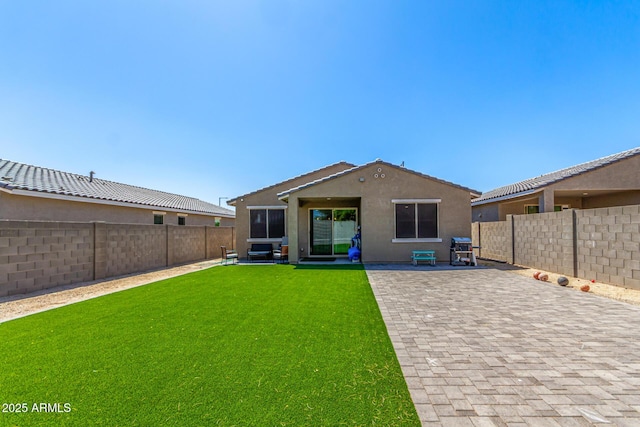 rear view of house featuring a lawn, a patio area, stucco siding, and a fenced backyard