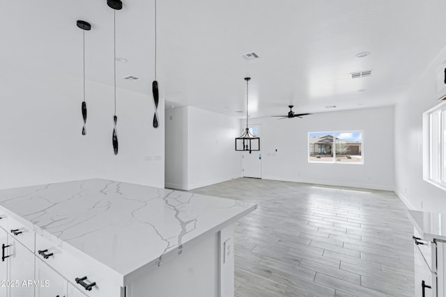 kitchen with light stone counters, white cabinets, and visible vents