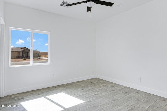 spare room with visible vents, ceiling fan, light wood-style flooring, and baseboards