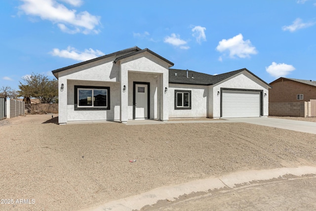 ranch-style home featuring concrete driveway, fence, an attached garage, and stucco siding