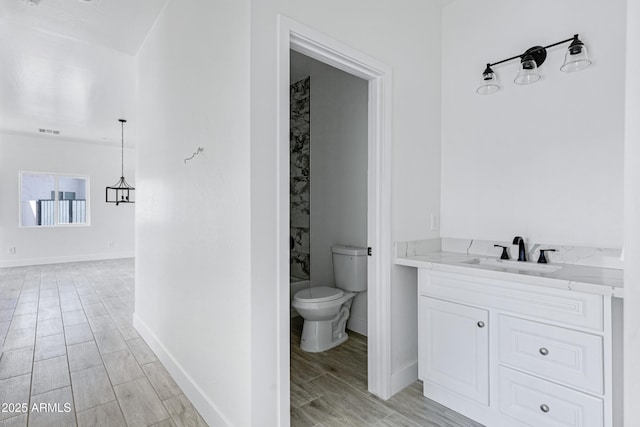 full bathroom featuring wood finish floors, visible vents, toilet, vanity, and baseboards