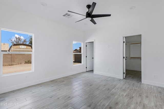 unfurnished bedroom featuring light wood-style flooring, multiple windows, visible vents, and baseboards