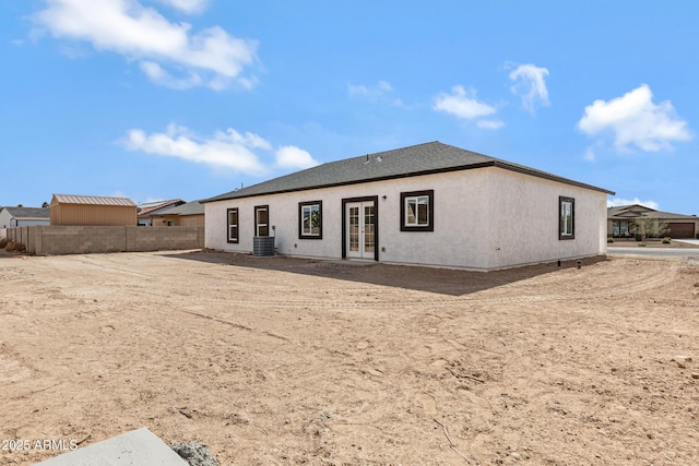 rear view of property featuring stucco siding, fence, cooling unit, and french doors