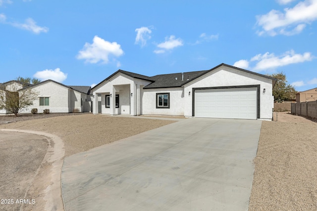 view of front of house featuring a garage, concrete driveway, fence, and stucco siding