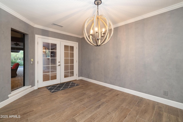 interior space featuring baseboards, ornamental molding, wood finished floors, french doors, and a notable chandelier