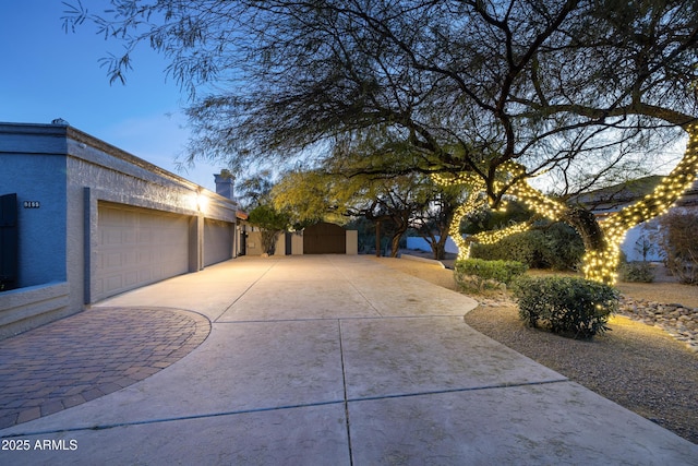 view of side of property featuring a garage, driveway, and stucco siding