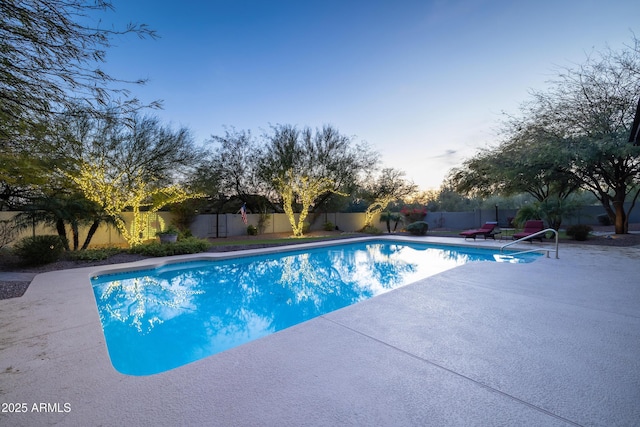 pool at dusk featuring a fenced backyard, a fenced in pool, and a patio