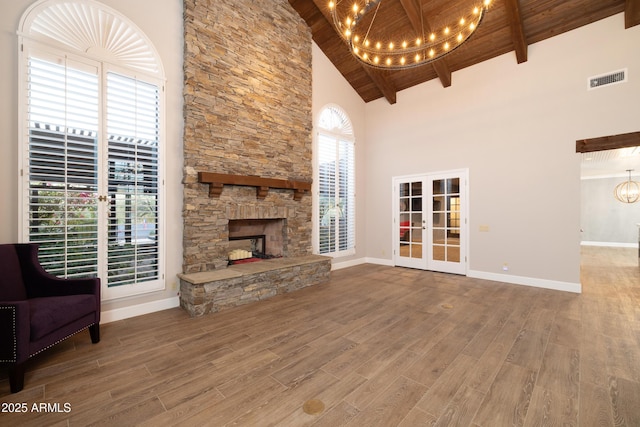 unfurnished living room with wood ceiling, wood finished floors, an inviting chandelier, french doors, and a fireplace