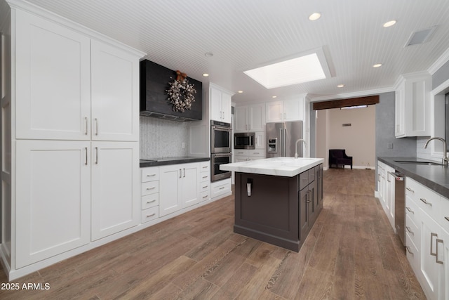 kitchen featuring stainless steel appliances, a center island, white cabinetry, and a sink