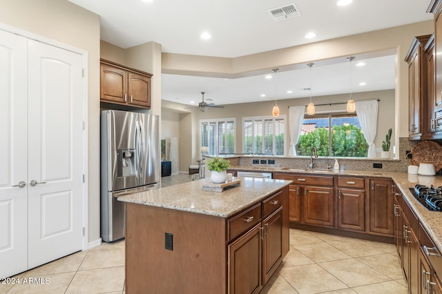 kitchen featuring backsplash, a center island, sink, ceiling fan, and stainless steel appliances