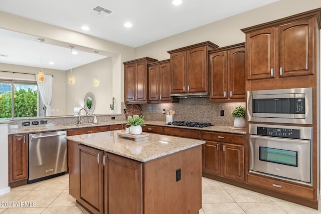 kitchen with light stone countertops, stainless steel appliances, decorative backsplash, and a kitchen island