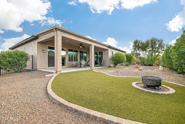 back of property with ceiling fan, an outdoor fire pit, a patio area, and a yard