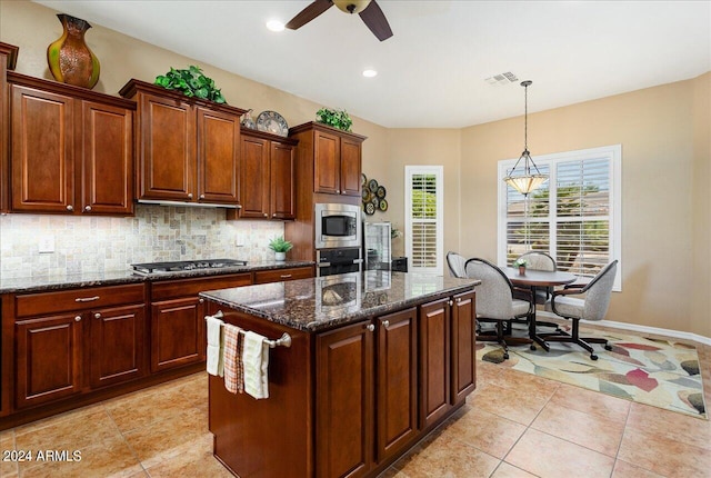 kitchen with light tile patterned floors, a center island, stainless steel appliances, and decorative backsplash