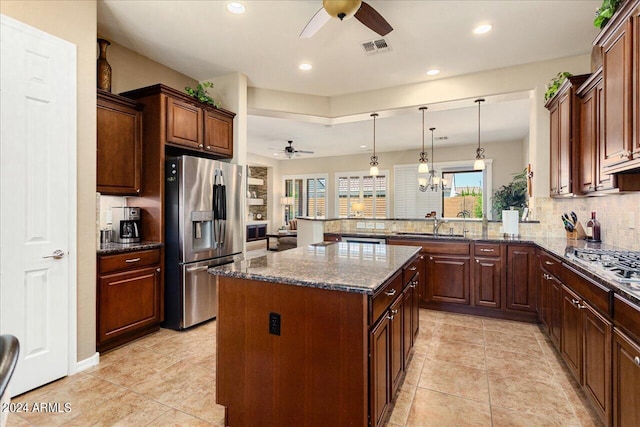 kitchen with appliances with stainless steel finishes, decorative backsplash, light tile patterned floors, a kitchen island, and ceiling fan