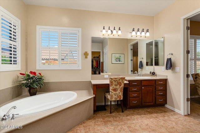 bathroom with a washtub, a wealth of natural light, tile patterned floors, and vanity