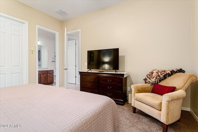 bedroom with connected bathroom and light carpet