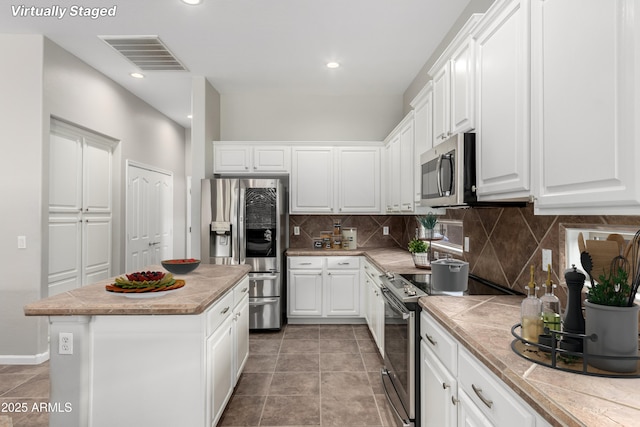 4215 W Hackamore Dr, Phoenix, AZ 85083 - kitchen with stainless steel appliances, tasteful backsplash, white cabinetry, a center island, and light countertops