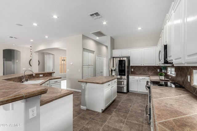 4215 W Hackamore Dr, Phoenix, AZ 85083 - kitchen with appliances with stainless steel finishes, a spacious island, arched walkways, a sink, and tasteful backsplash