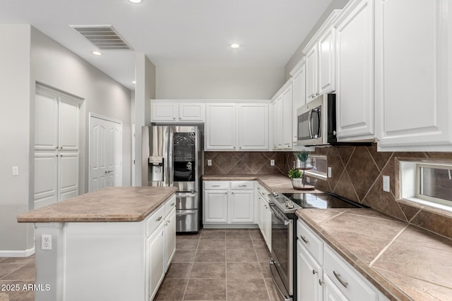 4215 W Hackamore Dr, Phoenix, AZ 85083 - kitchen with stainless steel appliances, a kitchen island, tasteful backsplash, white cabinetry, and tile countertops