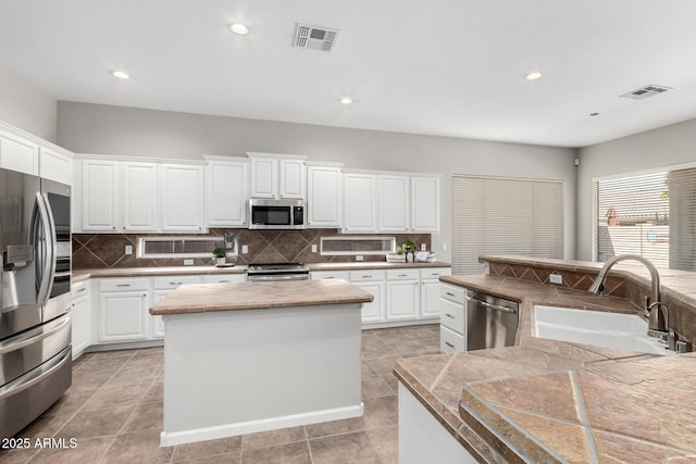 4215 W Hackamore Dr, Phoenix, AZ 85083 - kitchen featuring appliances with stainless steel finishes, a sink, a kitchen island, backsplash, and white cabinets