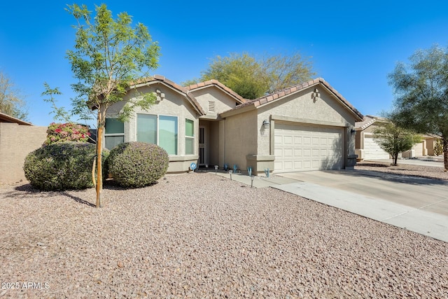 view of front of home featuring stucco siding, driveway, a tile roof, and a garage