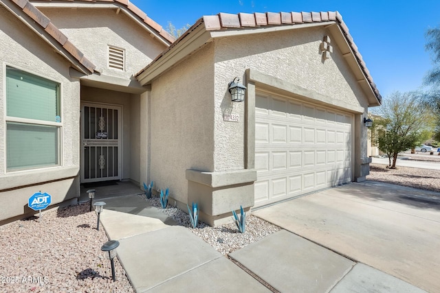 exterior space with concrete driveway, an attached garage, and stucco siding