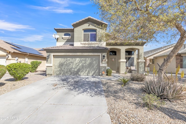 mediterranean / spanish-style house featuring a tiled roof, a garage, driveway, and stucco siding