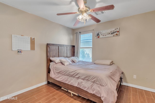 bedroom featuring baseboards, visible vents, ceiling fan, and wood finish floors