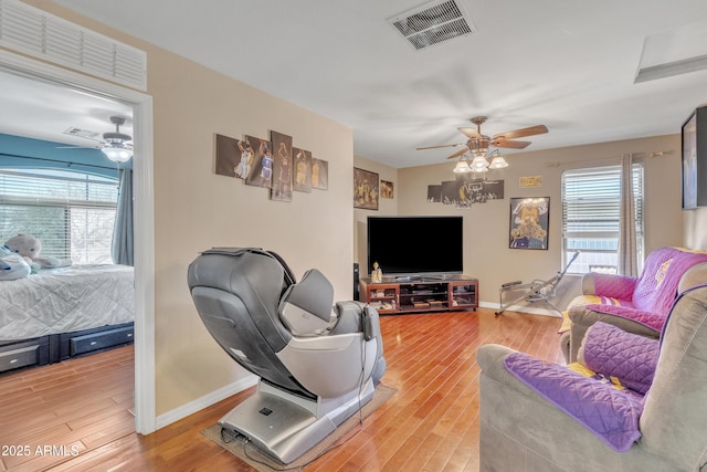 living area featuring light wood finished floors, a healthy amount of sunlight, visible vents, and a ceiling fan
