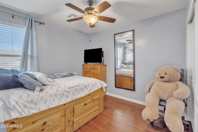 bedroom featuring visible vents, baseboards, ceiling fan, and wood finished floors