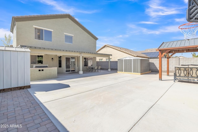 back of house with a shed, an outdoor structure, a fenced backyard, a patio, and outdoor dining area