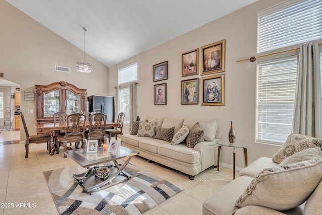 living area featuring light tile patterned flooring, high vaulted ceiling, baseboards, visible vents, and arched walkways