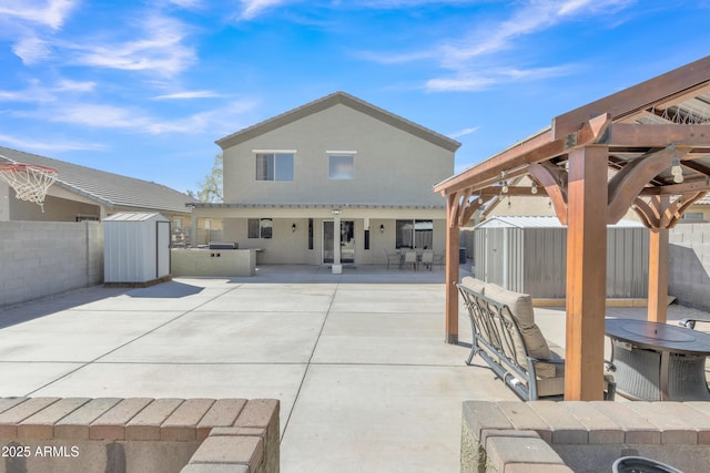 rear view of house featuring an outdoor structure, a shed, a patio, a fenced backyard, and a gazebo