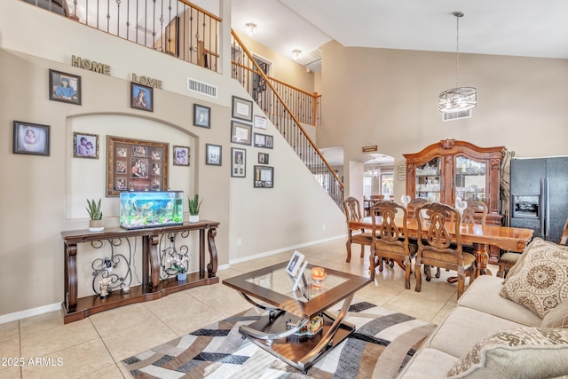 tiled living area featuring baseboards, visible vents, high vaulted ceiling, and arched walkways