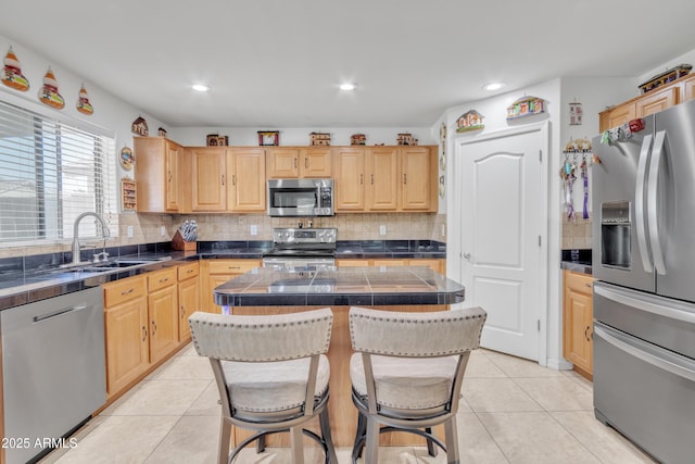 kitchen with a center island, light brown cabinetry, a kitchen breakfast bar, and appliances with stainless steel finishes