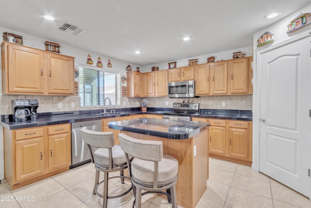 kitchen featuring light brown cabinets, visible vents, stainless steel appliances, and a sink