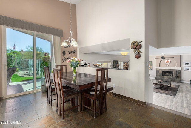 dining area featuring a towering ceiling and ceiling fan with notable chandelier