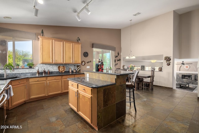 kitchen featuring sink, lofted ceiling, track lighting, decorative light fixtures, and a kitchen island